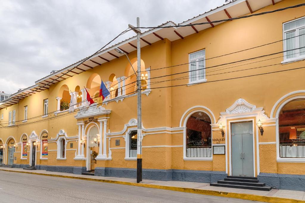 Gelbe Fassade des LP Los Portales Hotel Piura mit Rundbogenfenstern und Flaggen