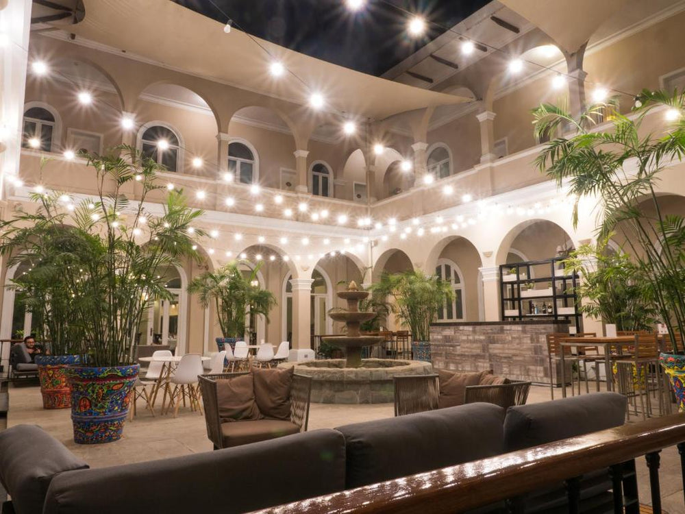 Beleuchteter Innenhof des LP Los Portales Hotel Piura mit Brunnen, Palmen und Sitzplätzen