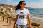Frau mit weißem Visited Lobitos T-Shirt vor Strand und Booten in Lobitos