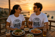 Paar mit weißen Visited Lobitos T-Shirts beim Sonnenuntergang an der Küste von Lobitos